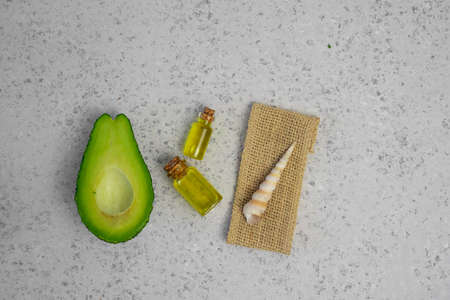 Natural products for skin care. Avocado oil in bottles near sliced avocado on grey background top view copy spaceの写真素材