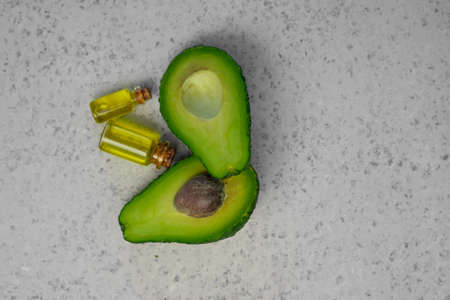 Natural products for skin care. Avocado oil in bottles near sliced avocado on grey background top view copy spaceの写真素材