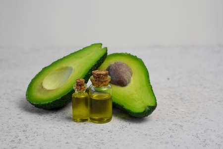 Natural products for skin care. Avocado oil in bottles near sliced avocado on grey background top view copy spaceの写真素材