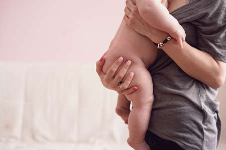 Babys buttock and feet in mothers and hands. Mother holds newborn on laps. Closeup shotの写真素材
