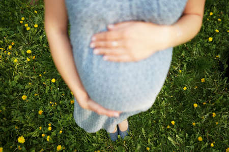 Close up of pregnant woman are relaxing in the garden at house. pregnant woman holding her belly and flower in the garden.の写真素材