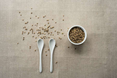 A white ceramic bowl full of hemp seeds over linen backgroundの写真素材