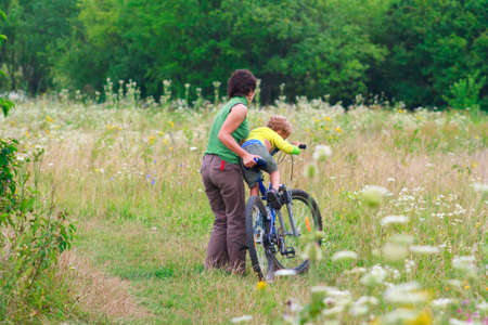 Mother and son are walking on a bike outdoorsの写真素材