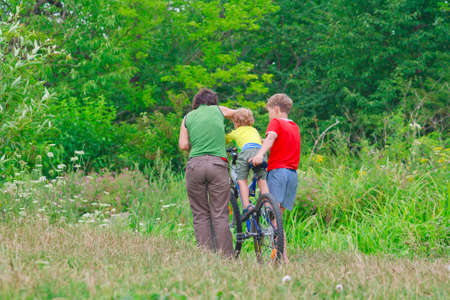 Mother and two sons are walking on a bike outdoorsの写真素材