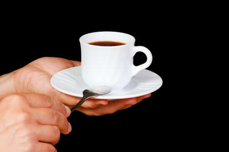 Hands with a cup of coffee on a black backgroundの写真素材