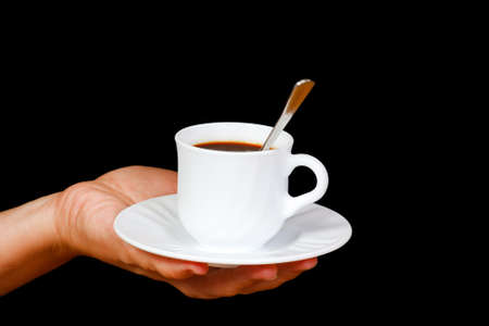 Hands with a cup of coffee on a black backgroundの写真素材
