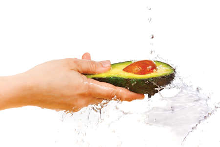 Fresh avocado in hand under flowing water on a white backgroundの写真素材