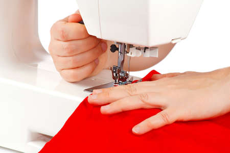 Hands of a seamstress at the sewing machine on a white background