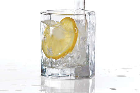 Glass of water, ice and slice of fresh lemon with splash on a white backgroundの写真素材