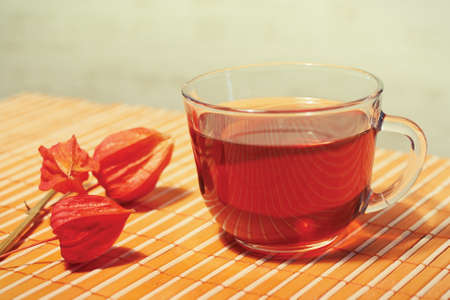 Cup of tea and physalis on a bamboo table cloth still lifeの写真素材