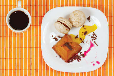 Cup of coffee, macaroons and caramel pudding on a bamboo table cloth still life