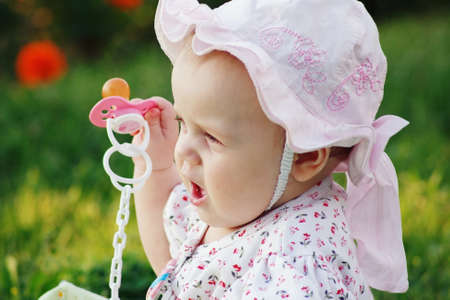 Portrait of a cute little girl with a pacifier in panama in the flower backgroundの写真素材