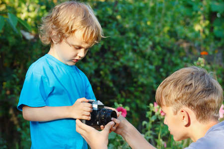 Young blond brothers with a camera outdoorsの写真素材