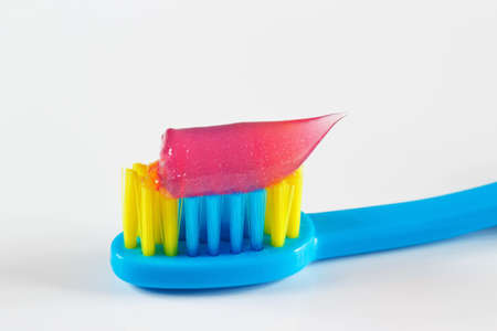 Blue toothbrush with pink toothpaste for child on white backgroundの写真素材