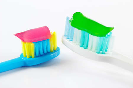 White and blue toothbrushes with toothpaste on white backgroundの写真素材