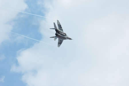 Flying tactical jet fighter MiG-29 make maneuvers in the cloudy sky
