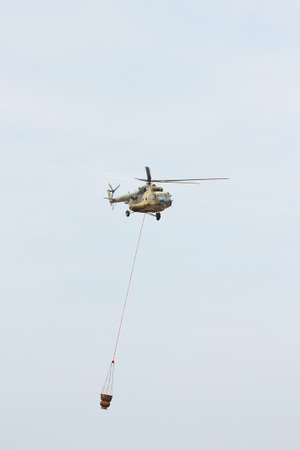 Russian military helicopter MI-8 extinguishes the fire with water in the cloudy skyのeditorial素材