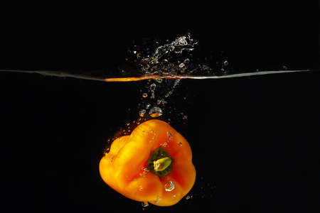 Pepper falling into the water with a splash on a black background の写真素材
