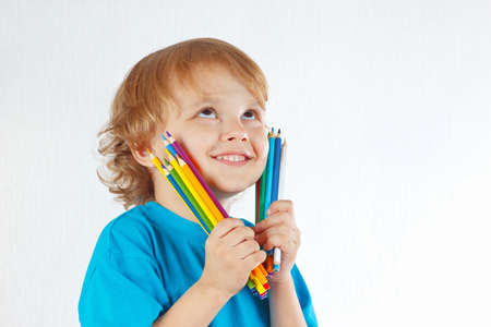 Little cute boy holds color pencils on a white backgroundの写真素材