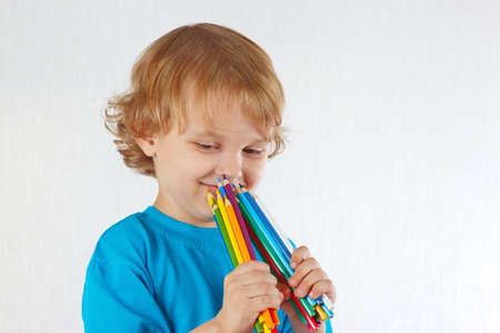 Young cute boy holds color pencils on a white backgroundの写真素材