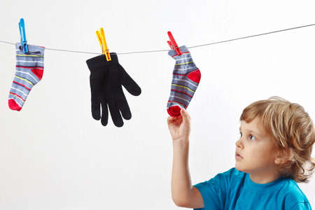 Little boy hanging your clothes on a white backgroundの写真素材