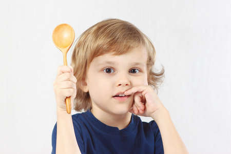 Little boy holding a wooden spoon on white backgroundの写真素材