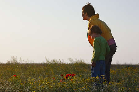 Mom and her son looking at the setting sun in the spring steppeの写真素材