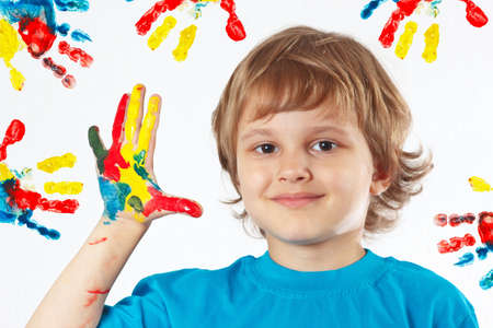 Young boy with painted hands on a background of hand printsの写真素材