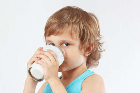 Little blonde boy drinking a fresh kefir on white backgroundの写真素材