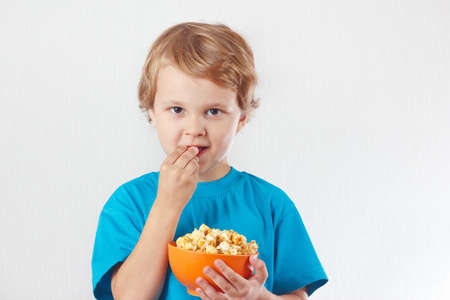 Young child eating popcorn on a white backgroundの写真素材