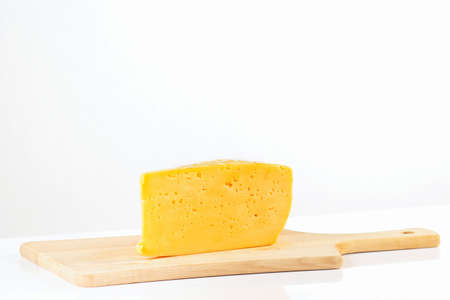 Piece of holland cheese on a wooden cutting board closeup