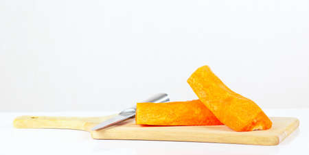 Halfs of fresh raw carrot with a knife on a cutting board closeupの写真素材