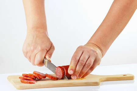 Female hands sliced salami on a cutting board close upの写真素材
