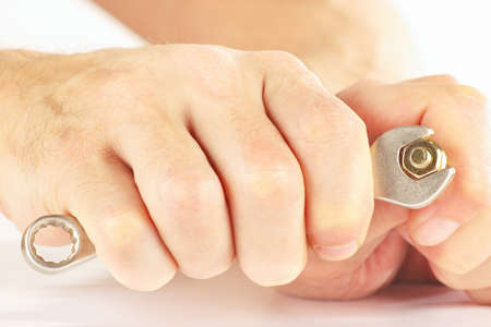 Hand of serviceman with a spanner to tighten the nut closeup