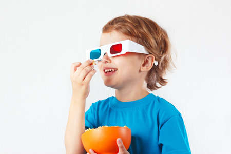 Young smiling boy in 3D glasses eating popcorn の写真素材