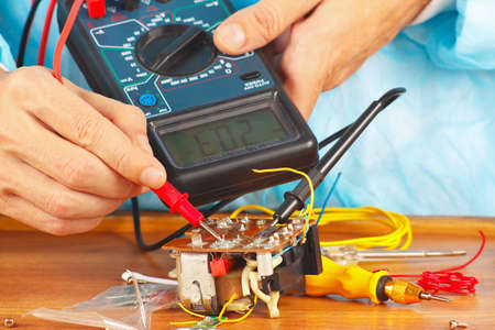 Serviceman checks electronic components of device with a multimeter の写真素材
