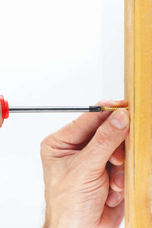 Hand tightening the screw into the wooden wall on a white backgroundの写真素材