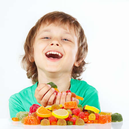 Smiling child with sweets and candies on a white backgroundの写真素材