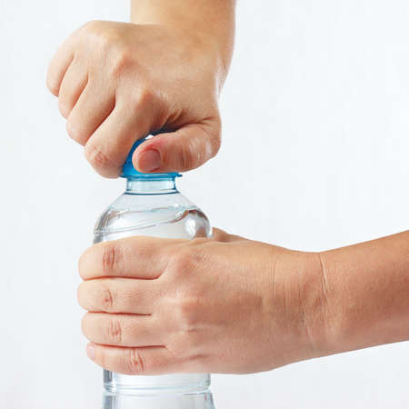 Hands opening a bottle of fresh water on white backgroundの写真素材