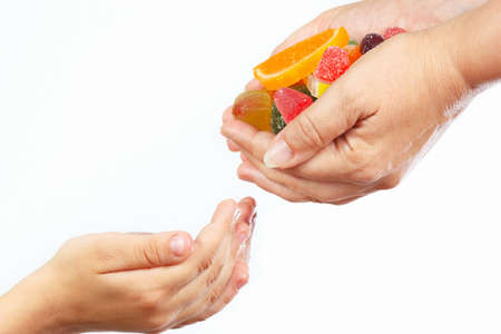 Hands of mother give colorful candies and sweets in hands child closeupの写真素材
