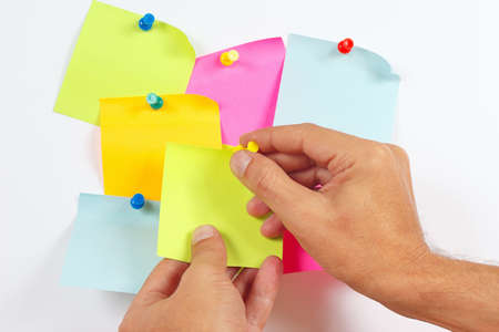 Hand attaches orange sticker on a white message board
