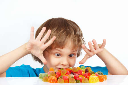 Little boy with colored jelly candies on a white backgroundの写真素材