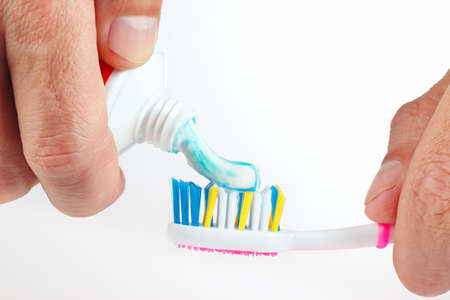Hand applied the toothpaste on the toothbrush on a white backgroundの写真素材