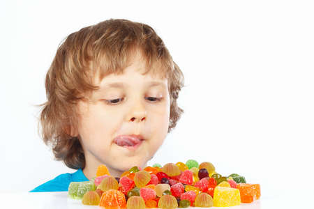 Little boy looking at colored jelly candies on a white backgroundの写真素材