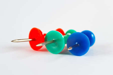 Blue, green and red  pushpins on the white paper close up