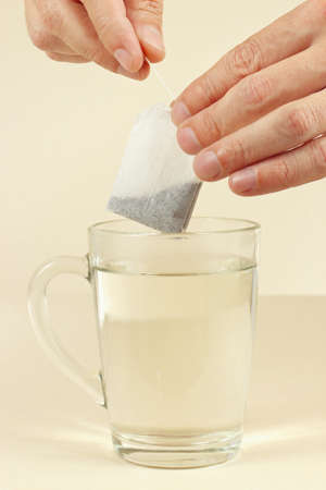 Hands are going to brew a tea bag in a cup of boiling waterの写真素材