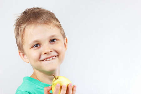 Little funny boy in a green shirt with yellow juicy pear