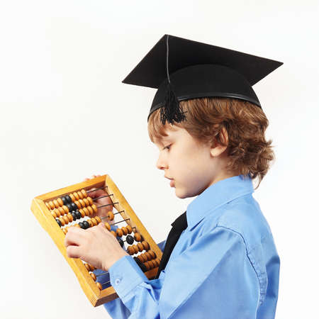 Little serious boy in academic hat with old abacus on a white backgroundの写真素材