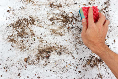 Hand with sponge wiping a dirty surfaceの写真素材
