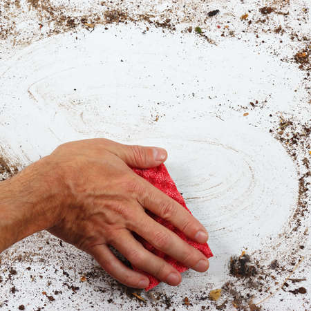 Hand with red sponge wiping a heavily dirty surfaceの写真素材